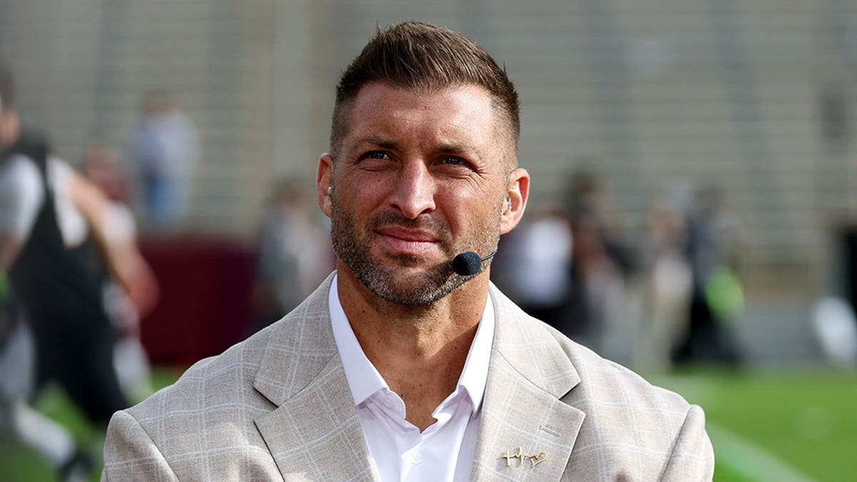 Tim Tebow stands on set before the CFP first-round game at Kyle Field.