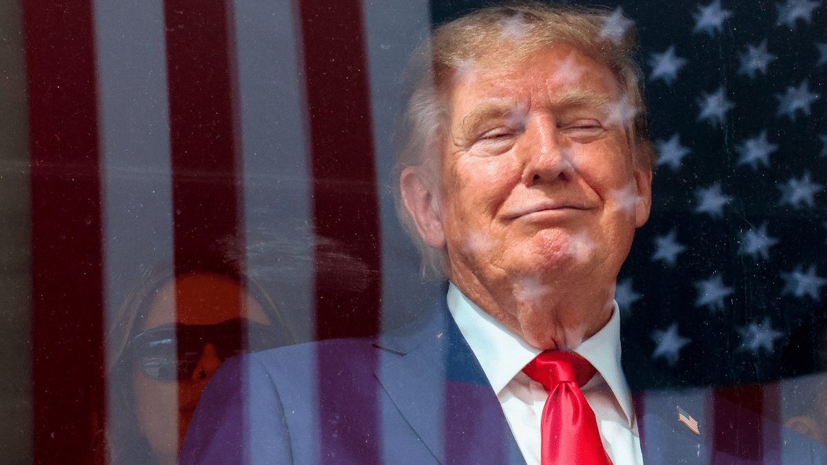 An American flag is reflected off bulletproof glass as U.S. President Donald Trump watches the end of the NTT INDYCAR Series on August 23, 2026 in Washington, DC.