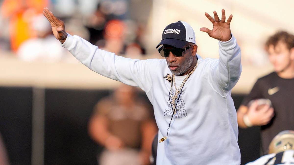 Deion Sanders stands on the field during Colorado's warmup before a college football game