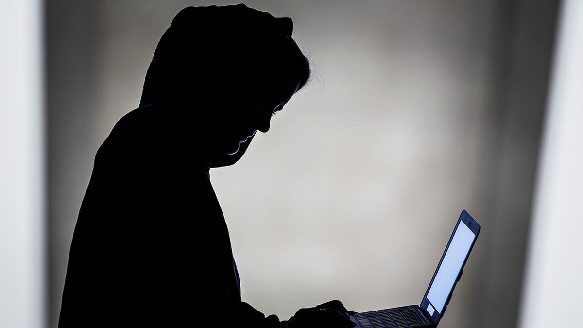 Hacker typing on a laptop.