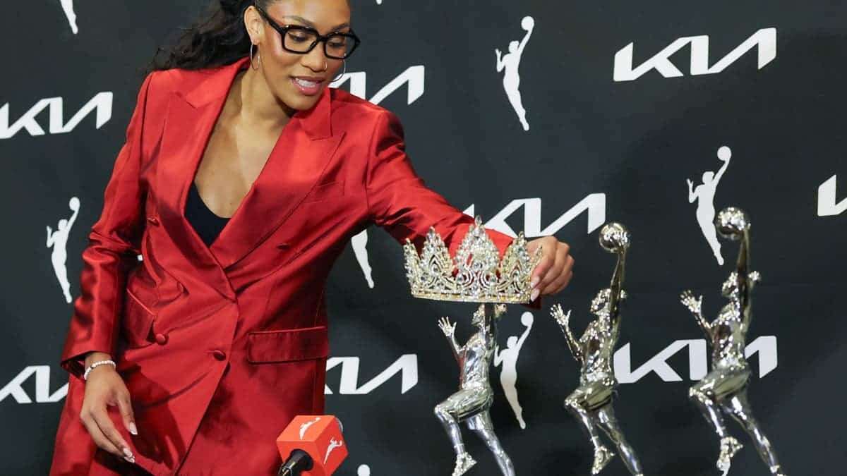 A'ja Wilson places a tiara over her 2026 WNBA MVP trophy at a news conference.