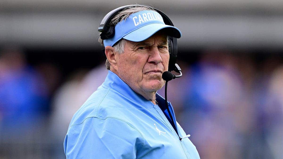 Bill Belichick stands on the sideline during an NCAA college football game.