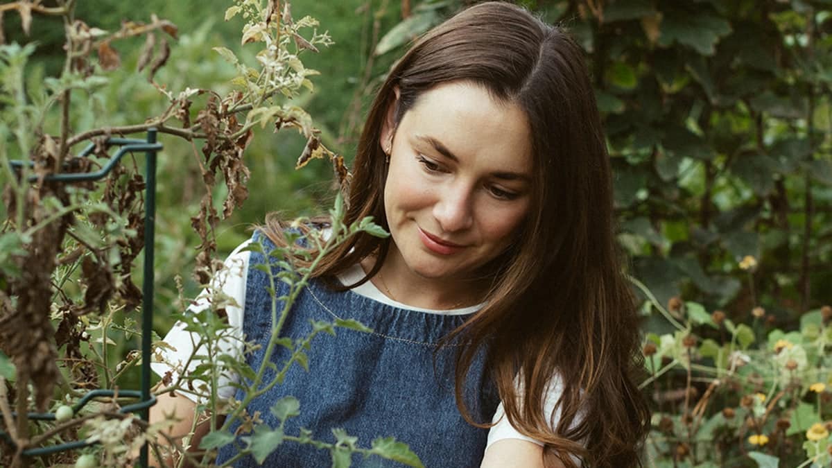 up-close of Carmen Perr in garden working with tomato vines.