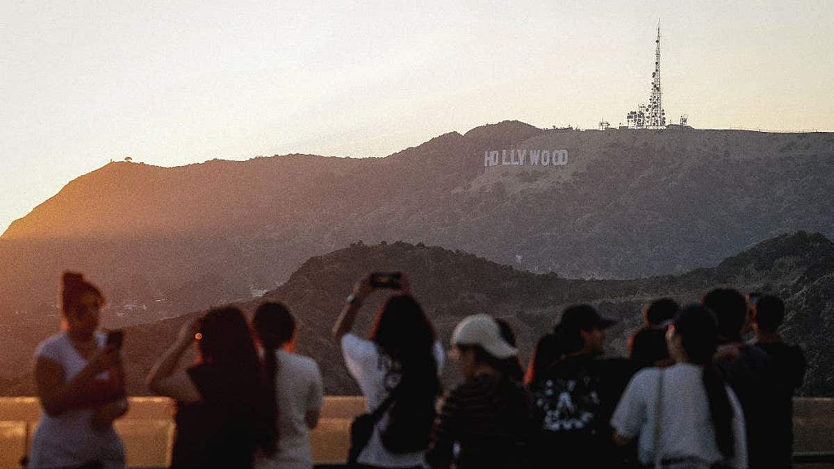 Crowds of people watch the sunset over the Hollywood sign from Griffith Observatory.