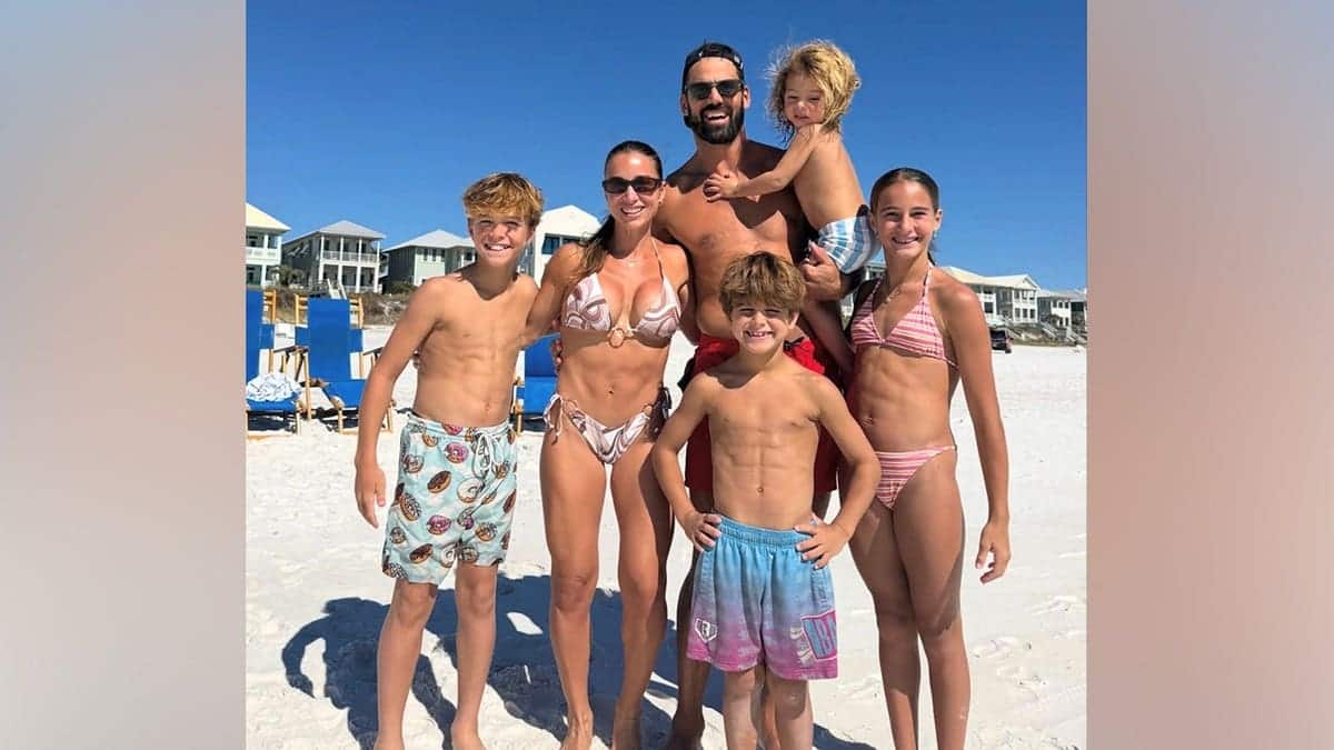 Jessie James Decker poses in a bikini with her shirtless husband, former NFL player Eric Decker, and their four children on a sandy beach in Florida.