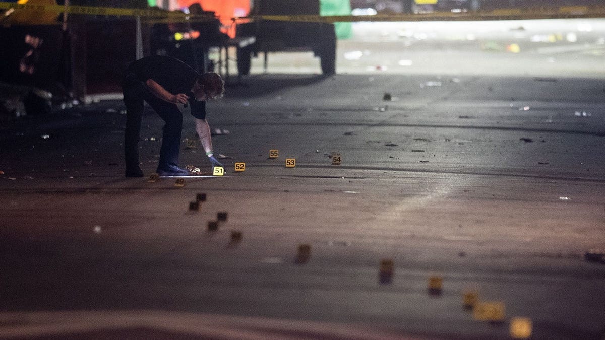 Investigator with flashlight examines evidence markers on Perry Street behind Bragg Memorial Stadium.