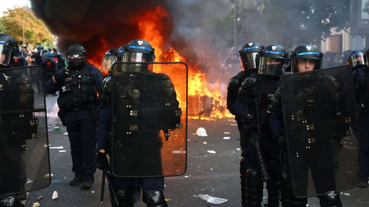 French riot police stand near burning objects during clashes with protesters in Paris.