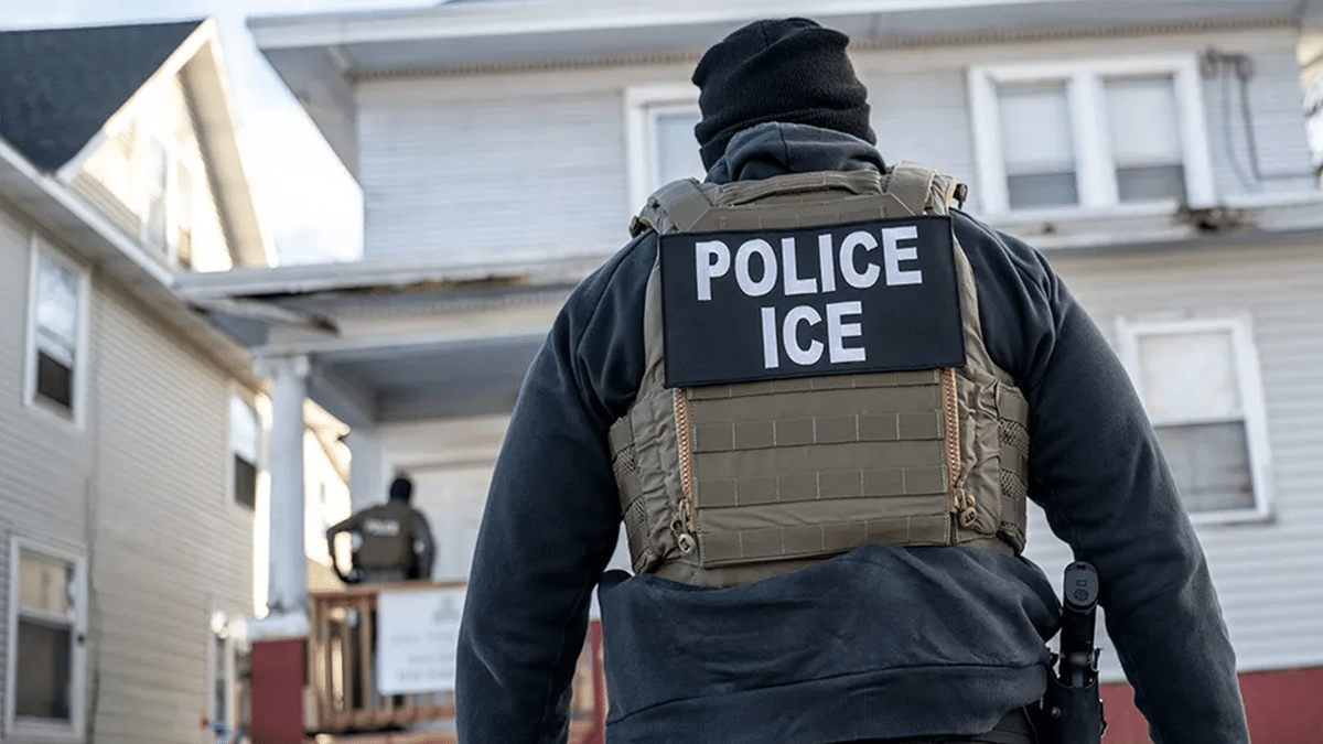 A federal law enforcement agent outside a home during a raid
