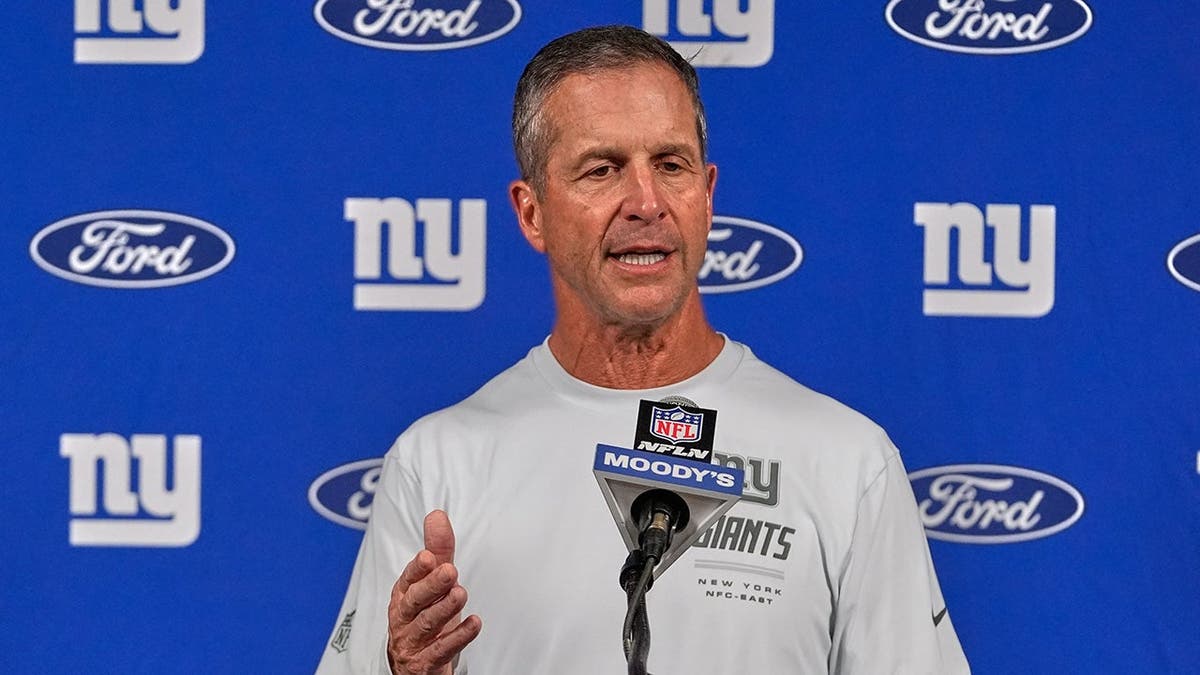 John Harbaugh talks with reporters following an NFL game in Houston.