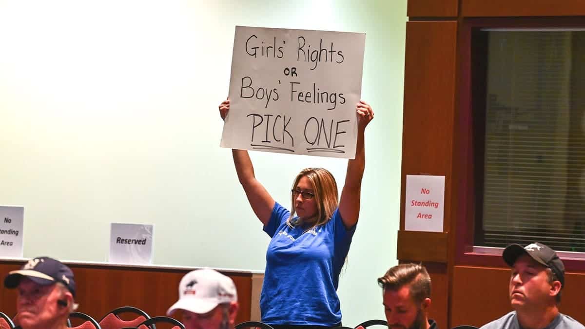 A mother holds up a sign reading