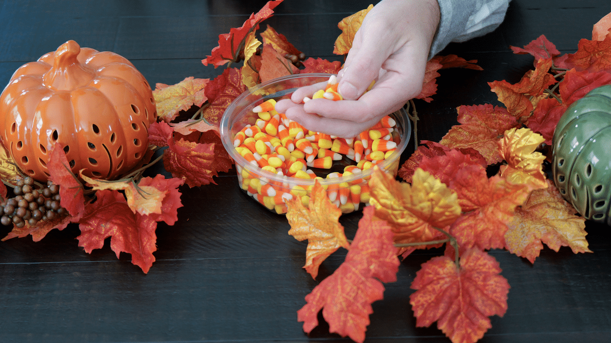 Man eating candy corn at a festive dinner table during Halloween.