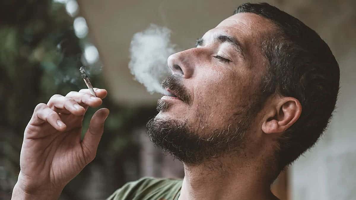 A man smokes marijuana surrounded by smoke.