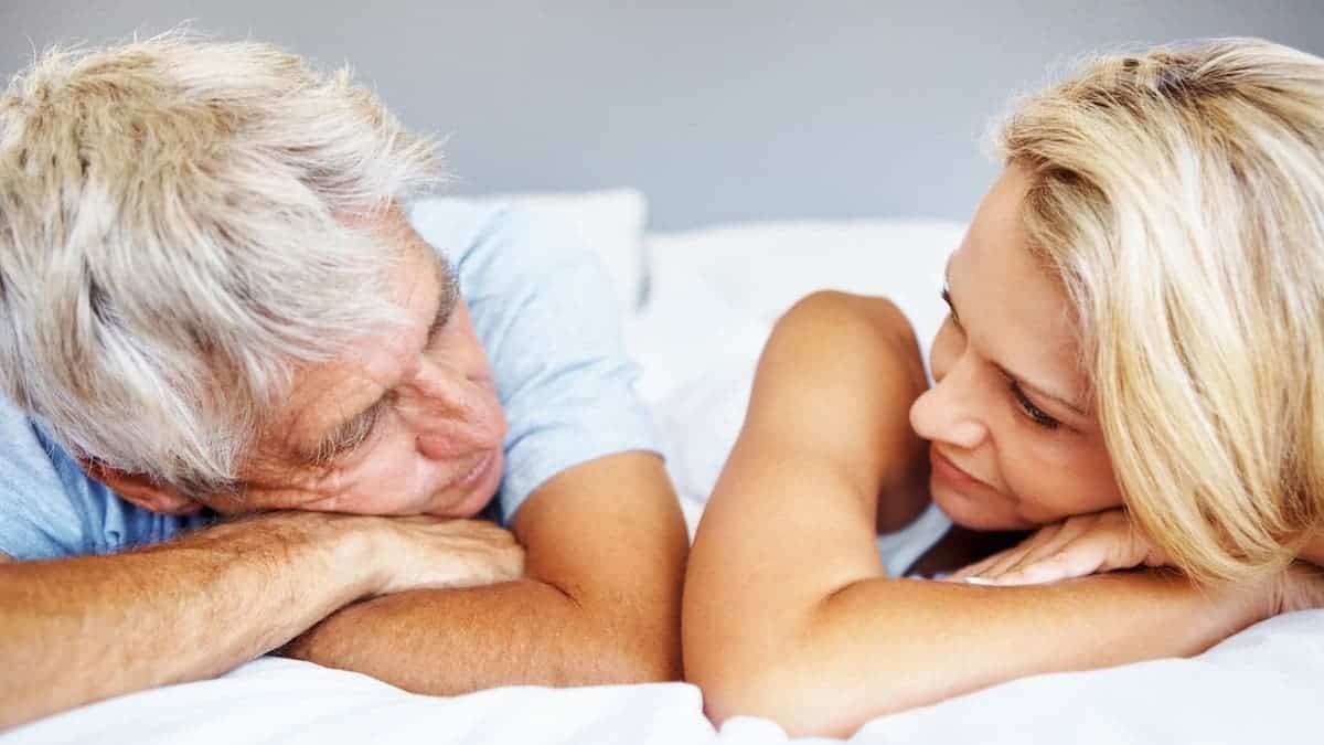 Mature couple lying in bed, looking at each other
