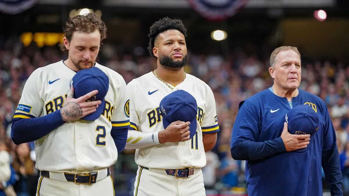Brice Turang, Jackson Chourio and Pat Murphy line up along the base path during the national anthem.