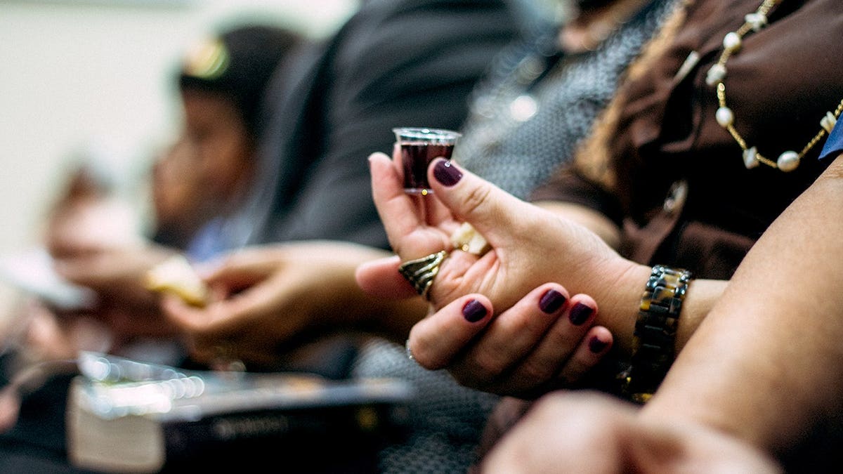 Person holds holy wine and prays in church.