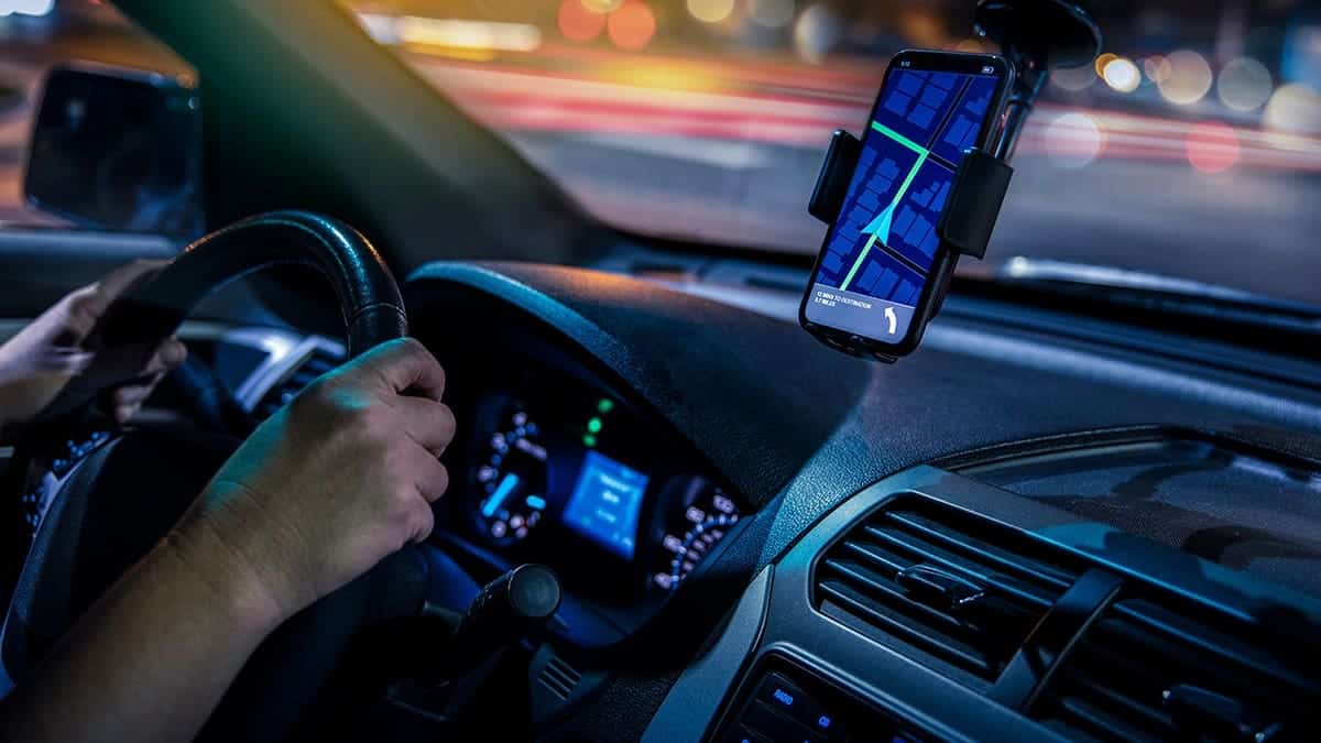 Phone-based GPS display glows on a smartphone mounted in a car at night.