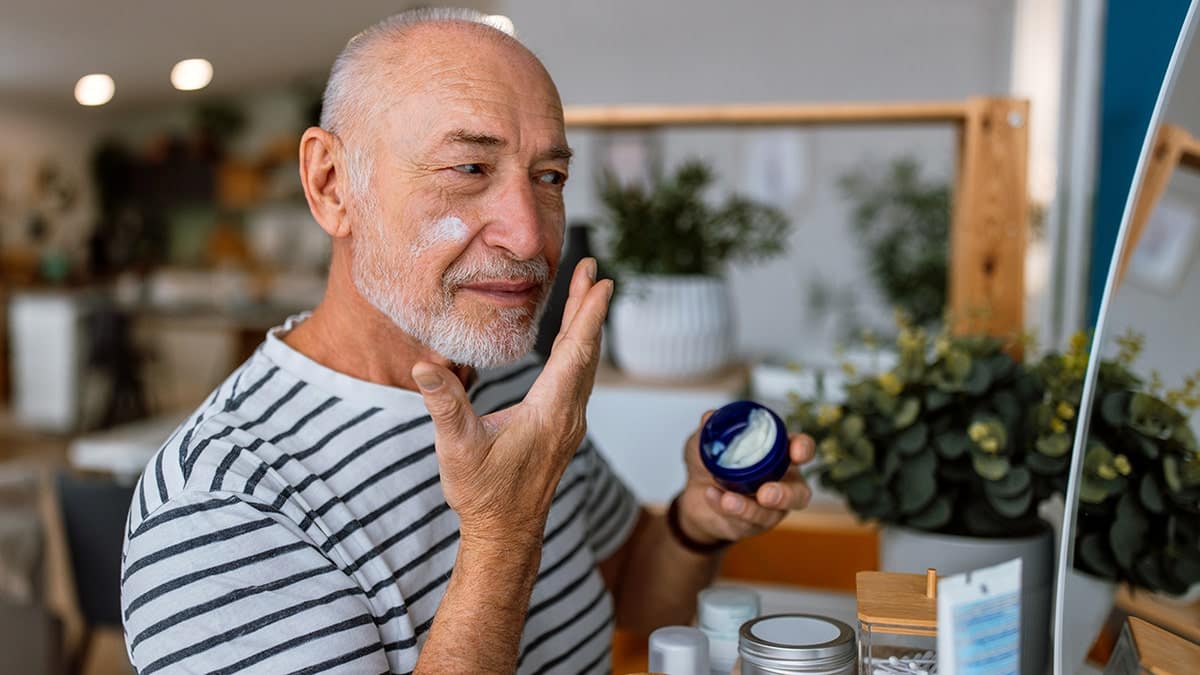 Handsome Senior Man Applying Cream at His Face in the Bathroom