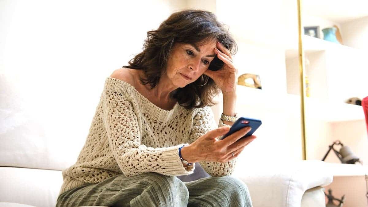 Senior woman looking at her phone with a worried expression.