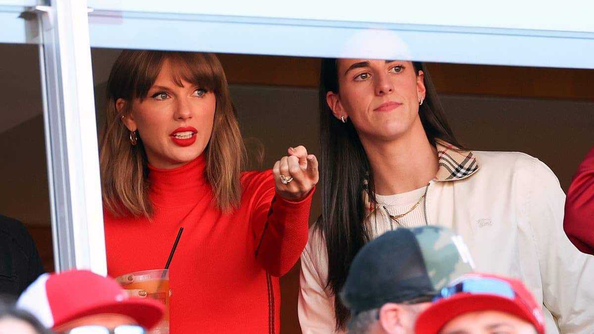 Taylor Swift and Caitlin Clark seated in stands watching a football game.