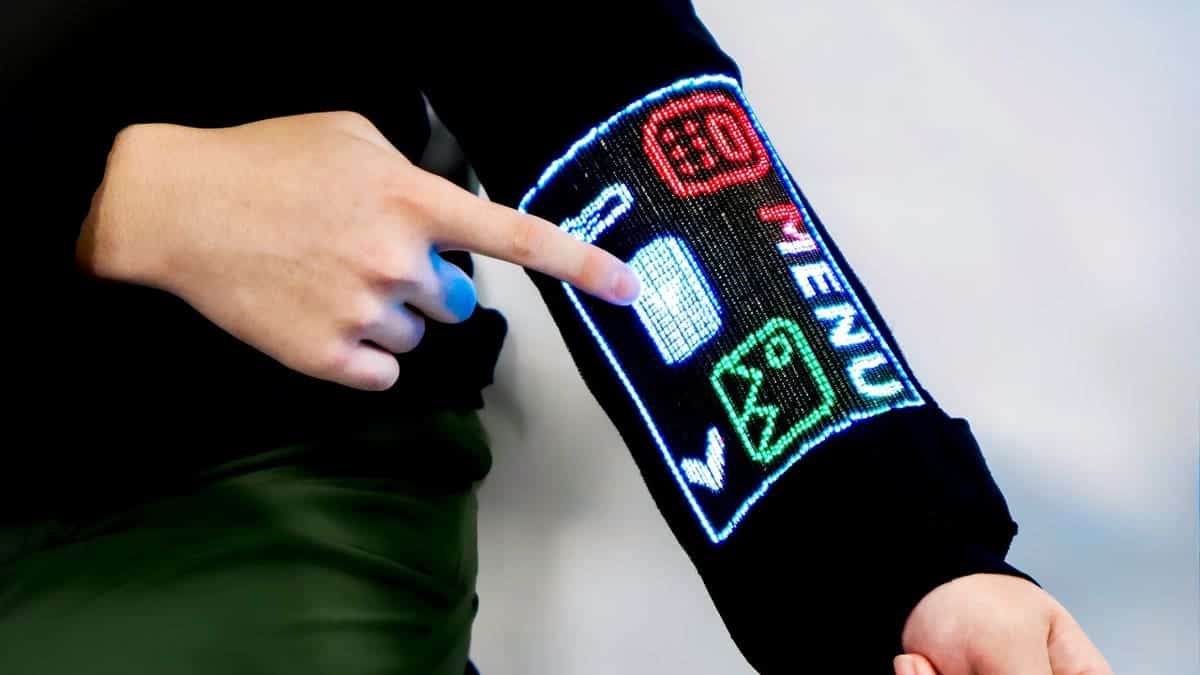A person touches a digital display on the sleeve of a shirt.