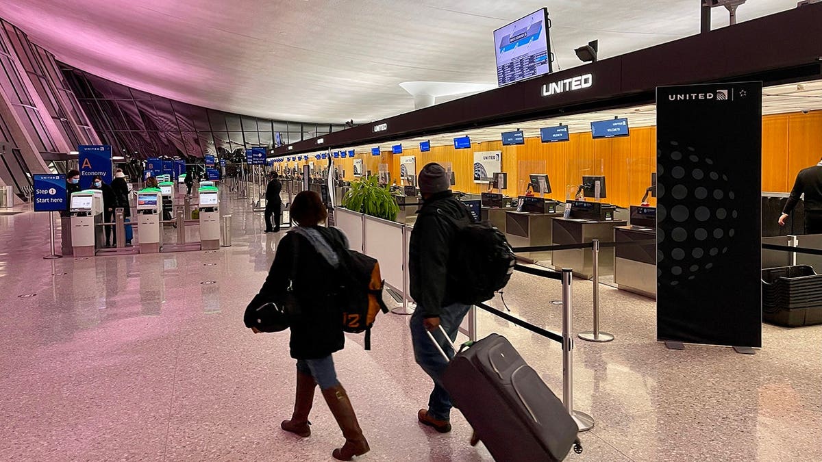 Travelers walk past a United Airlines counter at Dulles International Airport.