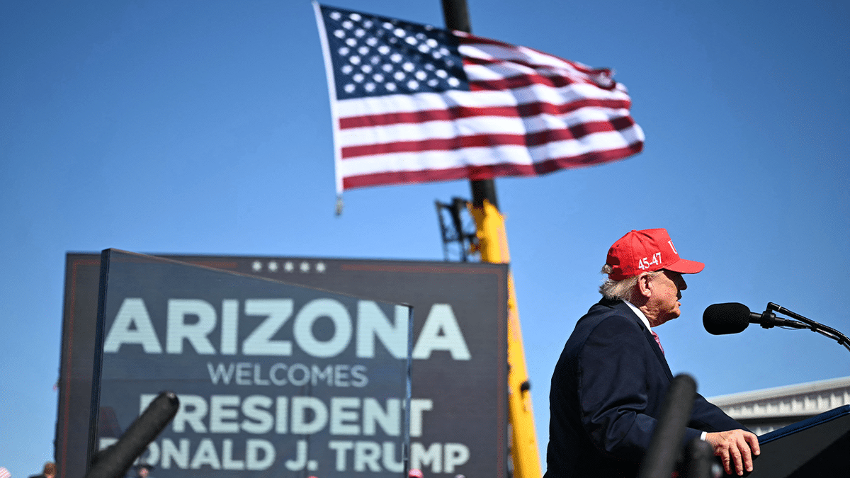 President Donald Trump speaks at a podium beneath an American flag during his Arizona campaign rally