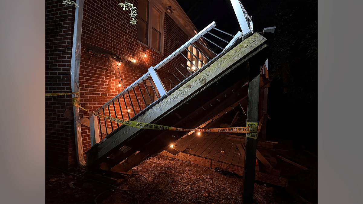 Collapsed wooden porch and broken railing behind police tape at a brick home in Williamsburg, Virginia